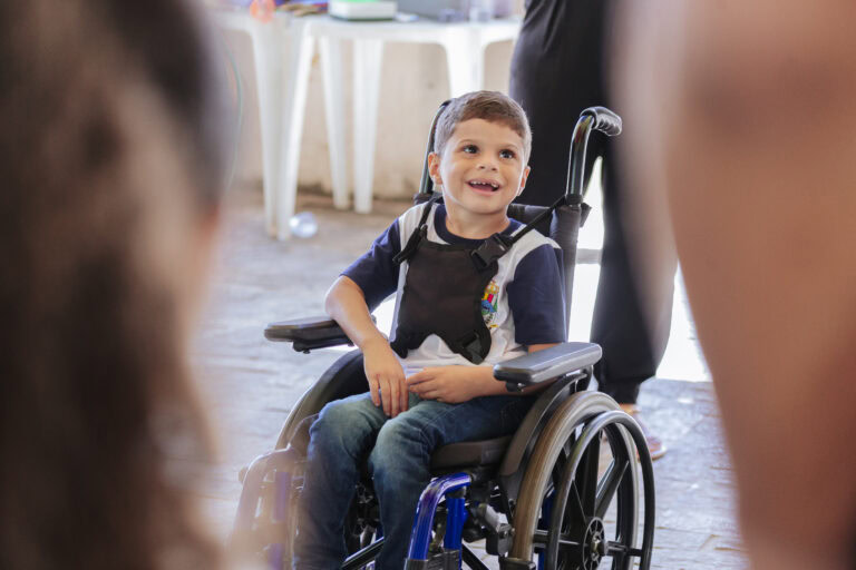A criança em cadeira de rodas participa do Festival Tenda Literária em Coroaci, promovendo inclusão.