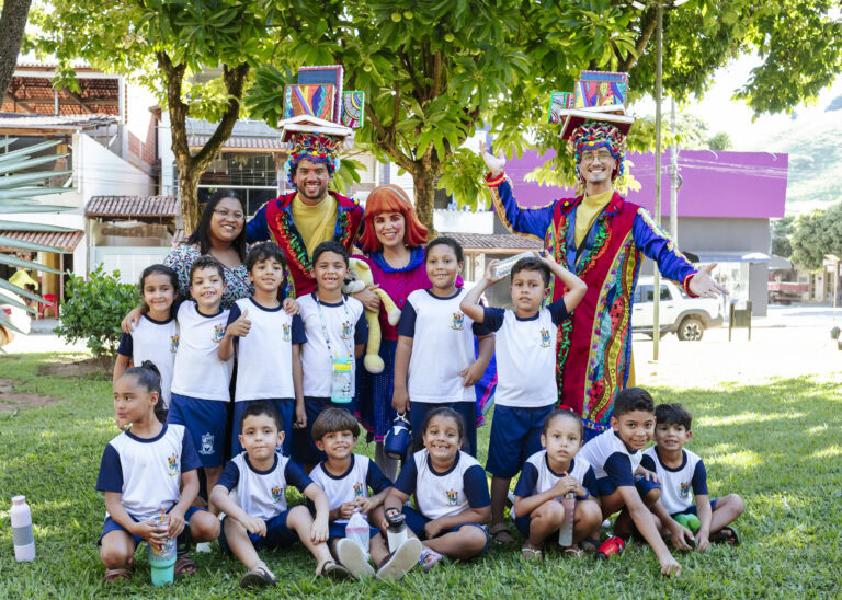 Imagem de crianças e palhaços em evento cultural ao ar livre.