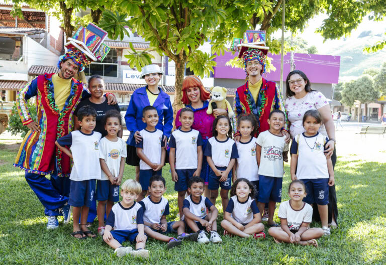 Imagem de crianças e adultos em evento literário ao ar livre.