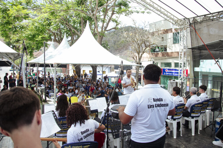 Encontro de Bandas de Música de Antônio Dias com músicos e público ao ar livre.