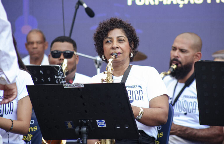 Encontro de Bandas de Música de Antônio Dias com músicos tocando instrumentos ao ar livre.