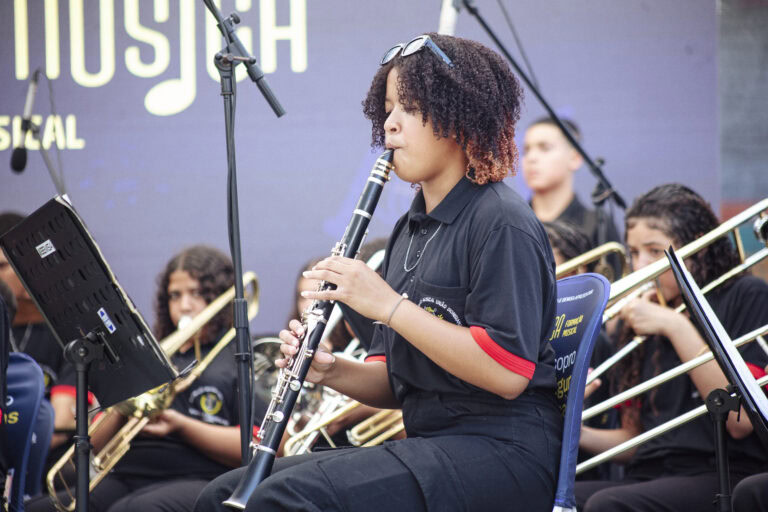 Performance de jovem músico tocando clarinete na apresentação de bandas locais.