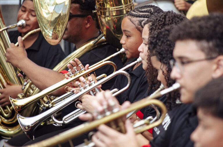 Participantes do encontro de bandas de música de Antônio Dias tocando instrumentos de sopro.
