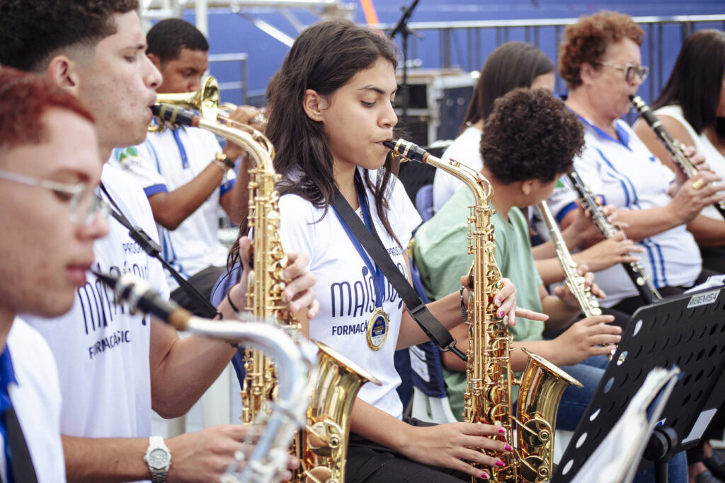 Imagem de jovens músicos tocando saxofone em encontro de bandas.