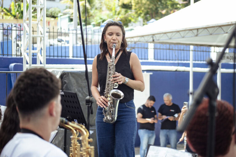Imagem de uma jovem tocando saxofone durante o Encontro de Bandas de Antônio Dias, evento cultural c.