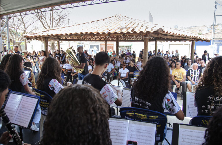 Encontro de bandas de música em Coronel Fabriciano, com músicos tocando ao ar livre durante evento c.
