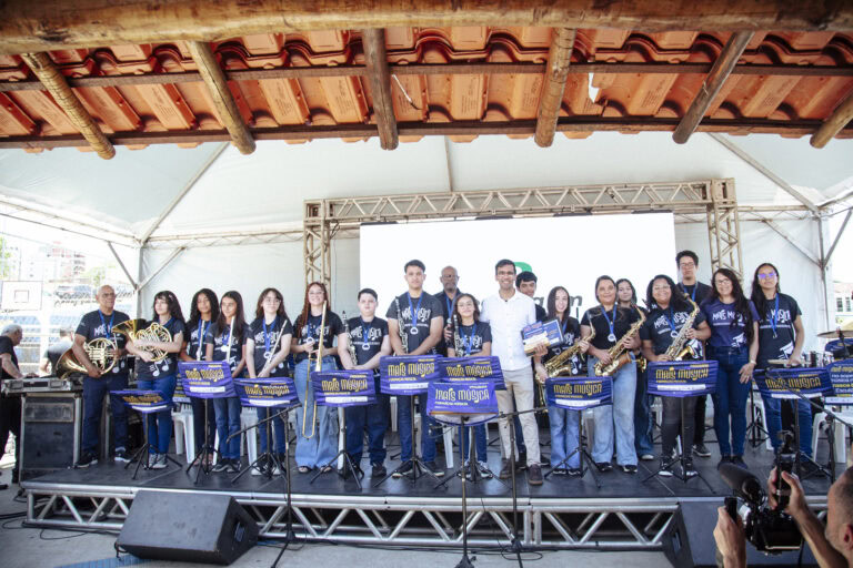 Encontro de Bandas de Música de Coronel Fabriciano com orquestra ao vivo no palco ao ar livre.