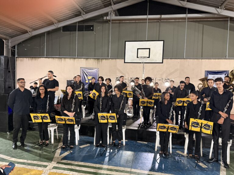 Banda de músicos tocando em evento do Encontro de Bandas de Música do Naque, com instrumentos e part.