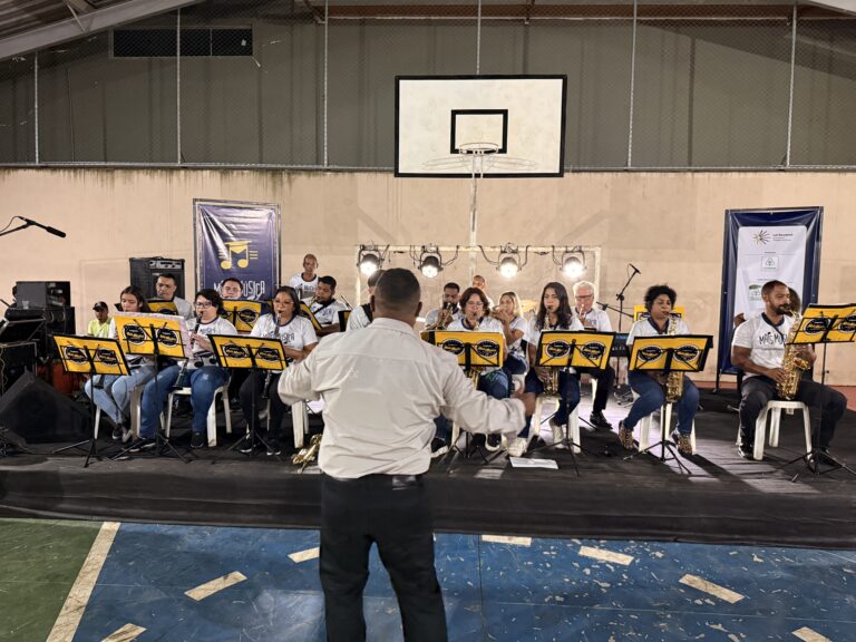 Banda de músicos tocando em evento de música na quadra de esportes de Naque.