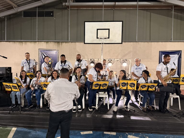 Banda de músicos tocando em evento de música na quadra de esportes de Naque.