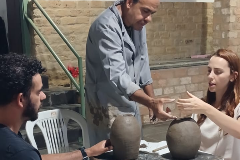 Artista mostrando técnicas de cerâmica para estudantes iniciantes.