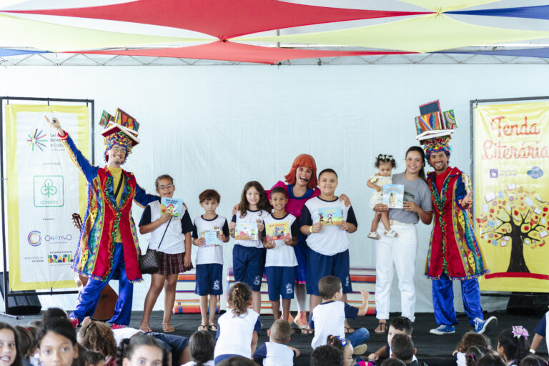 Atividades culturais na Tenda Literária com crianças e artistas em evento literário.