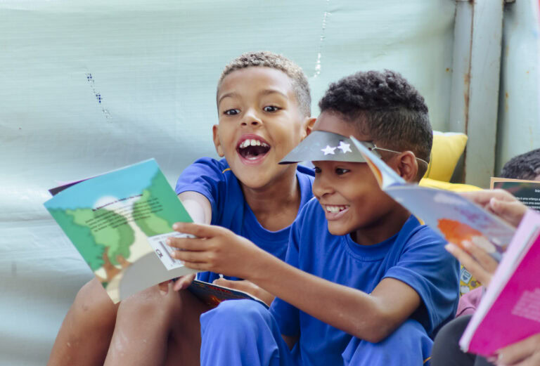 Tenda Literária Rio Vermelho manhã com crianças lendo livros e participando de atividades culturais.