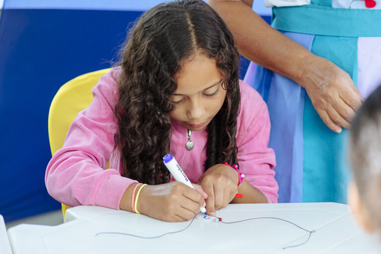 Criança escrevendo na Tenda Literária durante o festival matinal.