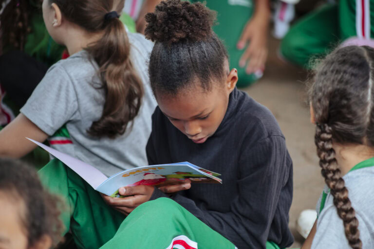 Criança lendo livro na Tenda Literária durante o Festival Rio Vermelho.