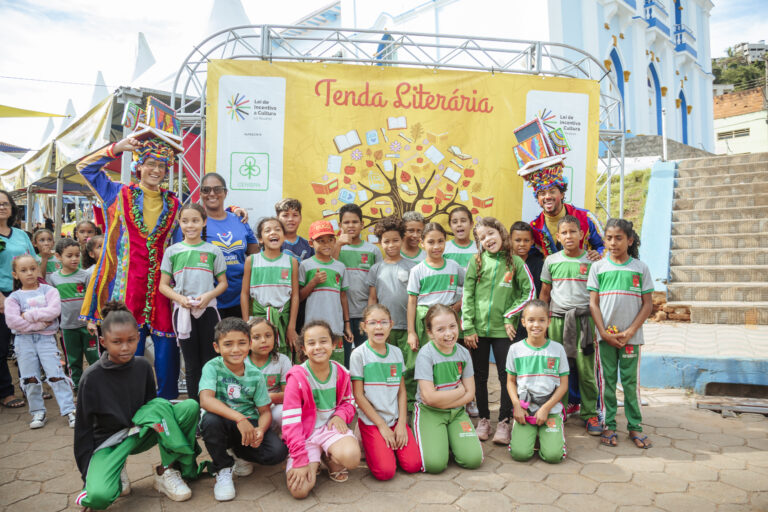 Evento infantil com crianças e artistas em frente à tenda literária.