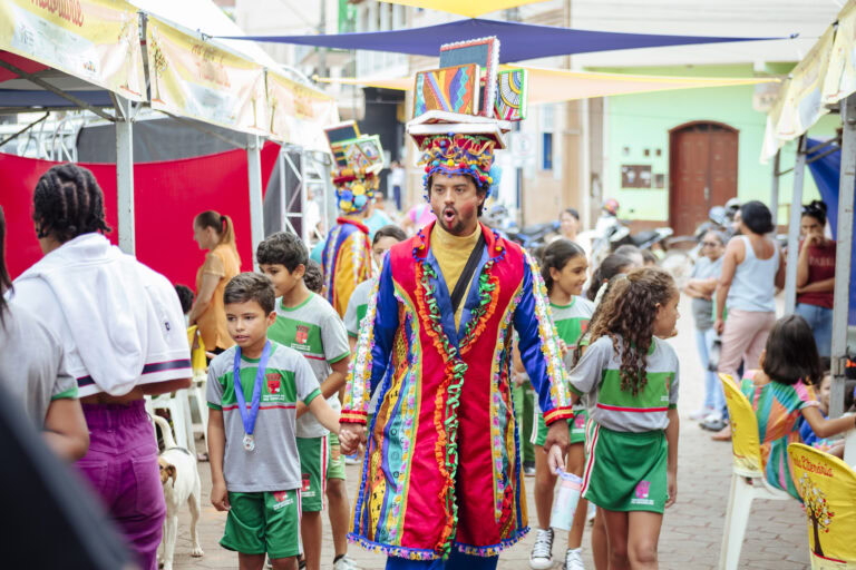 Ator vestido com fantasia colorida durante o Festival Tenda Literária Rio Vermelho à tarde.