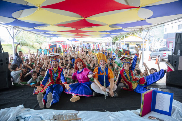 Atividades culturais e apresentações de artistas em evento literário ao ar livre.