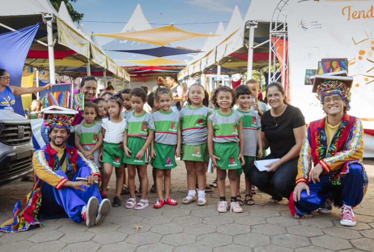 Imagem de crianças em uniforme escolar ao lado de artistas de circo na Tenda Literária Rio Vermelho,.