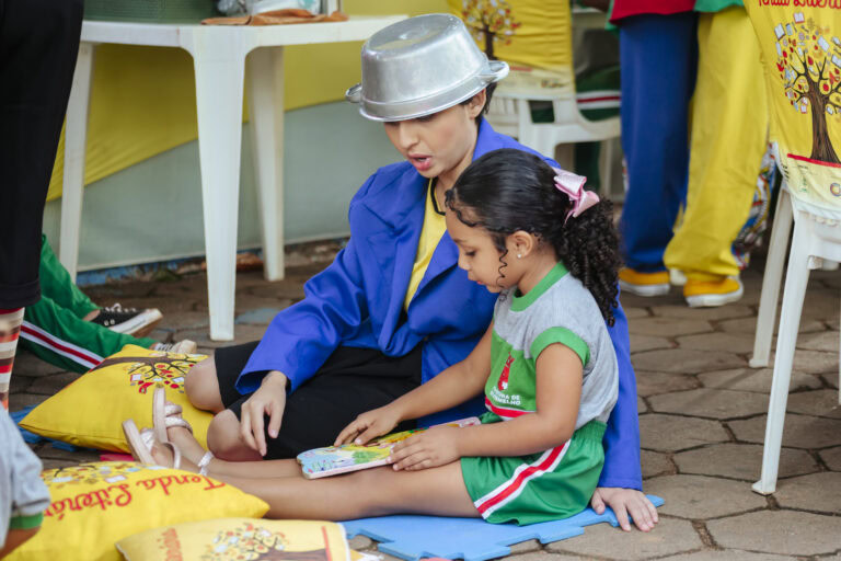 Criança e adulta lendo na Tenda Literária Rio Vermelho, evento cultural infantil.