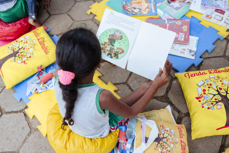 Imagem de criança lendo livro na Tenda Literária Rio Vermelho, evento cultural com atividades infant.