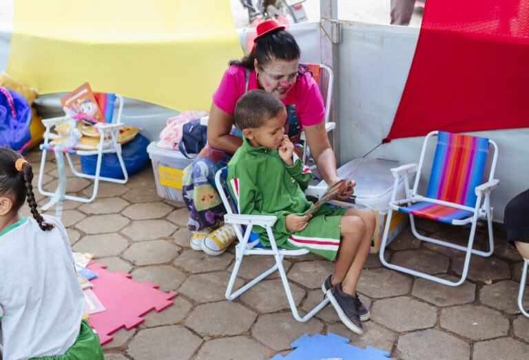 Imagem de uma criança lendo com uma monitora na Tenda Literária Rio Vermelho, evento cultural com at.