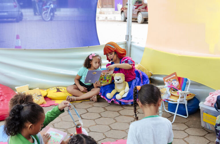 Imagem de crianças na Tenda Literária Rio Vermelho, participando de atividades de leitura e contação.