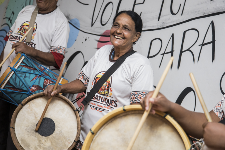 Imagem de mulheres tocando tambor em aula de tambatuques, celebrando cultura brasileira.