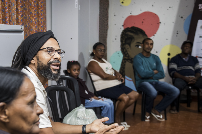 Aula de tambatuques com participantes atentos e envolvidos na atividade musical.