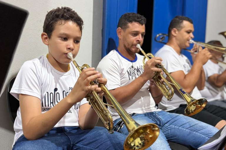 Jovens tocando trompetes em aula de música ao vivo.