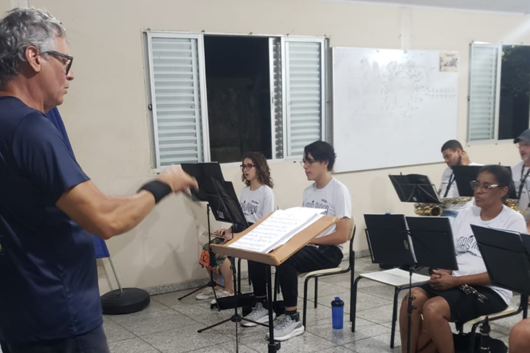 Ensaios de música com jovens músicos sob a orientação de um professor experiente.