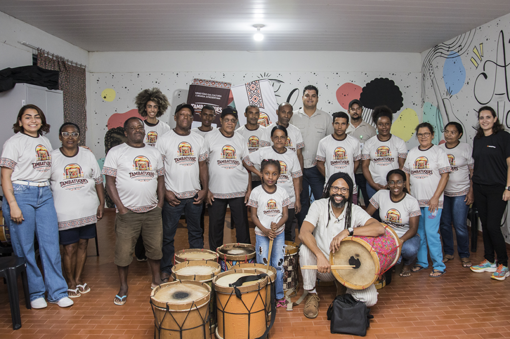 Aula de tambatuques com grupo diverso em atividade cultural e musical.