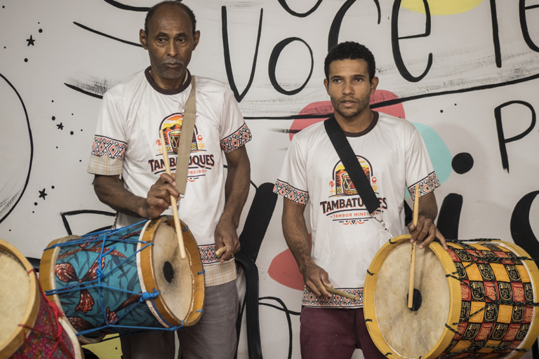Imagem de dois percussionistas tocando tambor com foco na aula especial de tambatuques.
