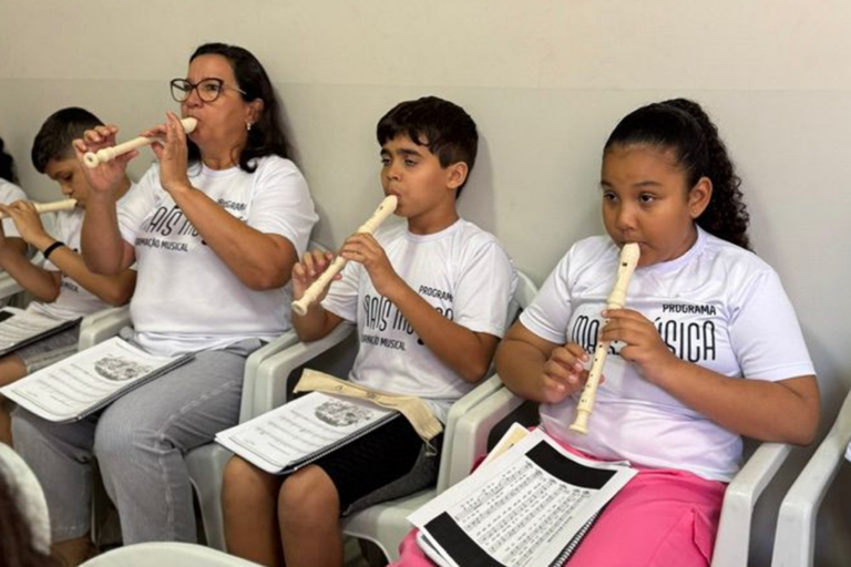Professora ensina crianças a tocar flauta doce na aula de música.