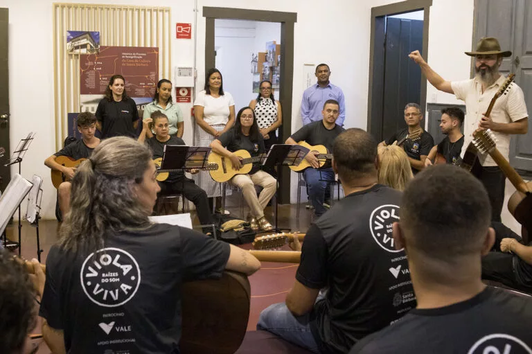 Apresentação de grupo de violas em evento cultural Viola Viva, com músicos e instrutor em aula inter.