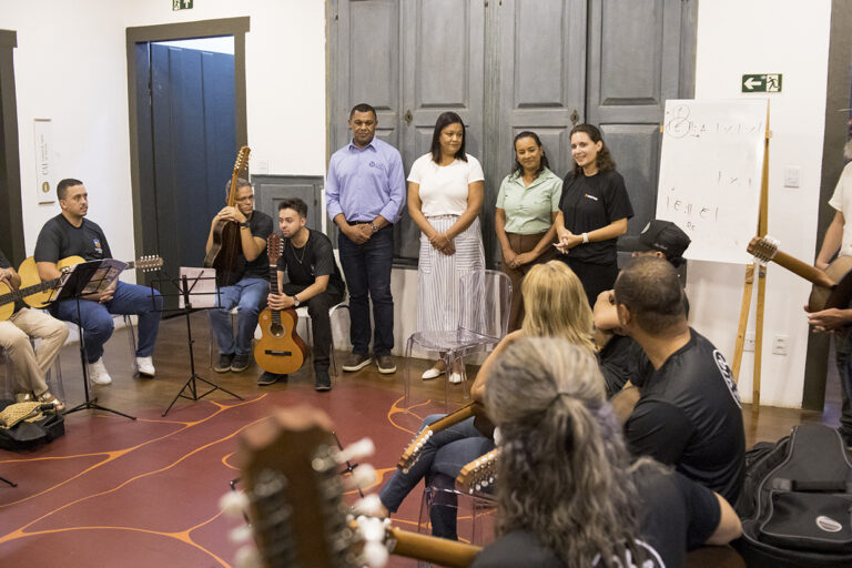 Imagem de músicos e participantes em ensaio para o evento Viola Viva, com instrumentos musicais e in.