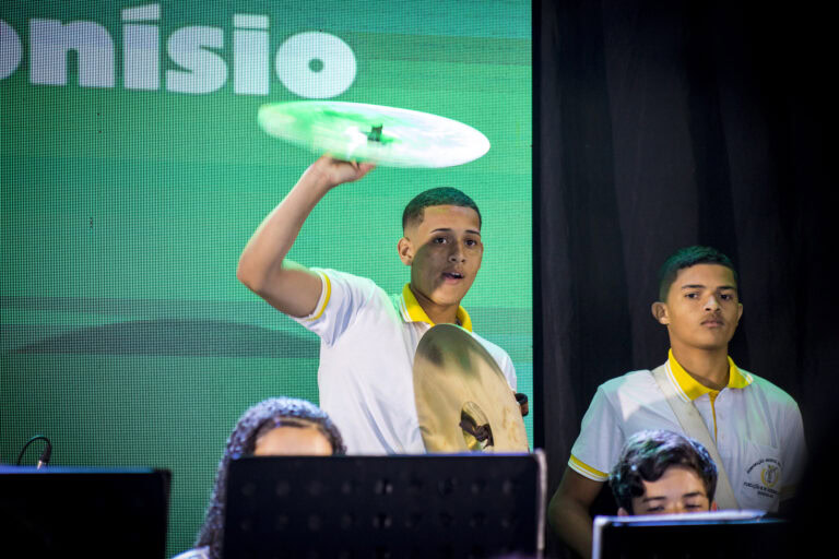 Jovem tocando tambor em apresentação musical ao vivo.