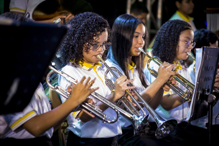 Jovens músicos tocando trompetes em apresentação ao vivo.
