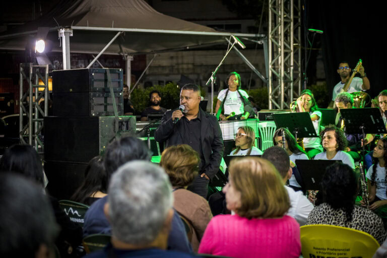 Performance musical ao vivo com banda e público em evento ao ar livre.