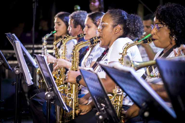 Grupo de músicos tocando saxofones em apresentação ao vivo.