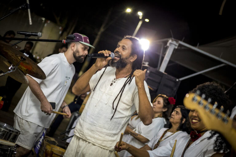 Grupo de músicos de Som de Minas tocando instrumentos tradicionais ao ar livre.