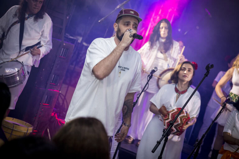 Performers em show ao vivo com instrumentos e microfone.