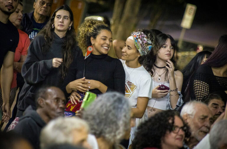 Pessoas sorrindo e conversando em evento cultural ao ar livre.