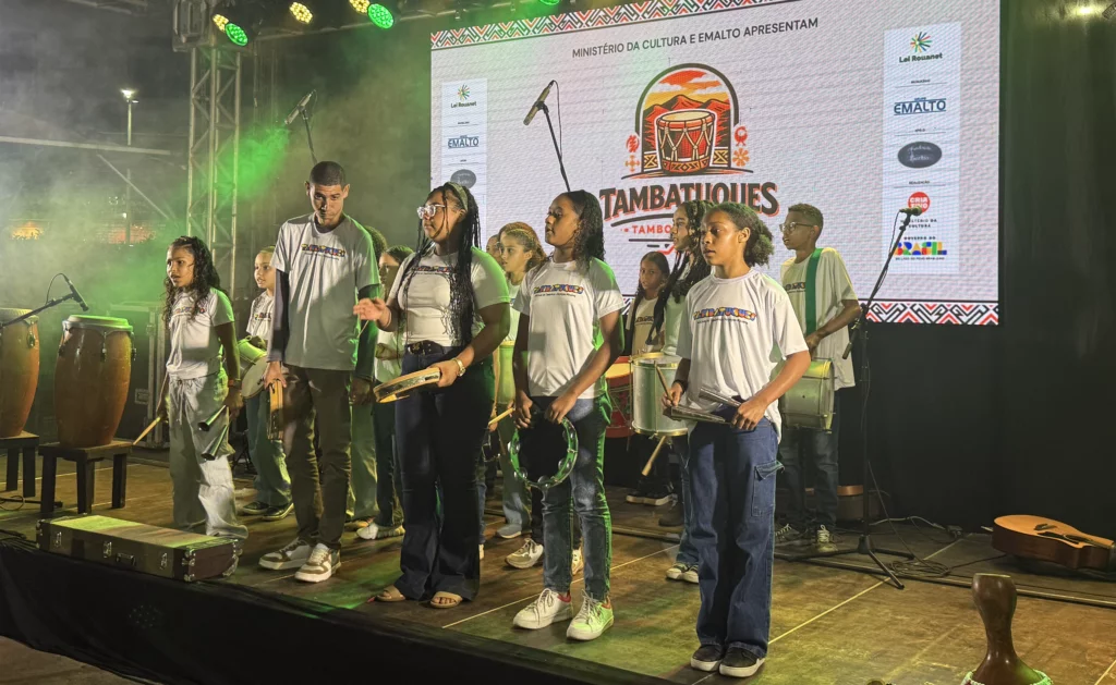 Grupo de crianças tocando tambor e instrumentos tradicionais no palco do Festival Tambatuques.