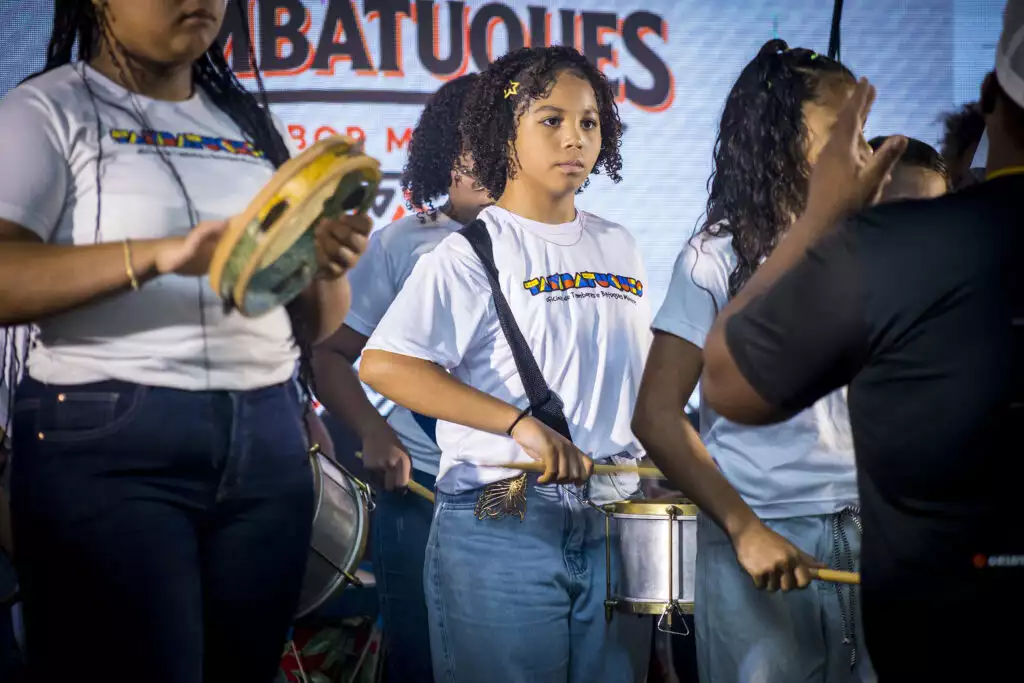 Jovens tocando tambor no Festival Tambatuques em apresentação cultural.