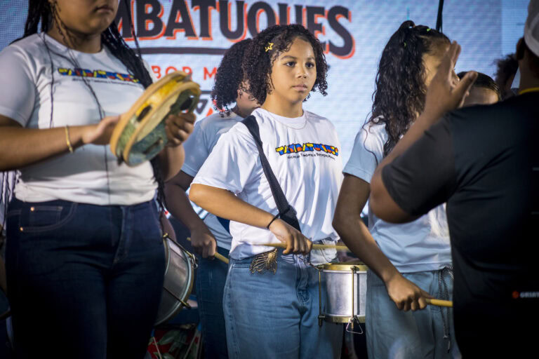 Jovens tocando tambor no Festival Tambatuques em apresentação cultural.
