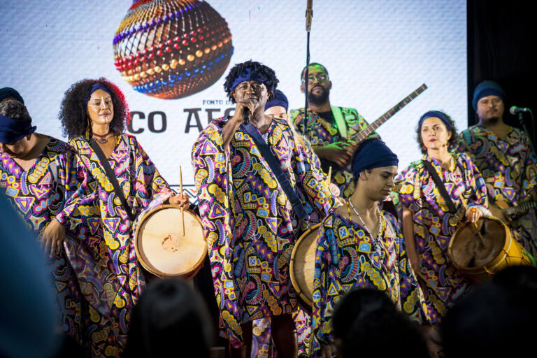 Grupo de músicos tocando tambor e instrumentos de percussão no Festival Tambatuques.