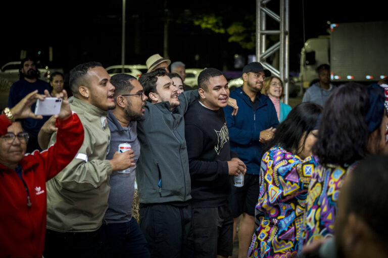 Pessoas assistindo ao show no Festival Tambatuques, evento cultural ao ar livre.